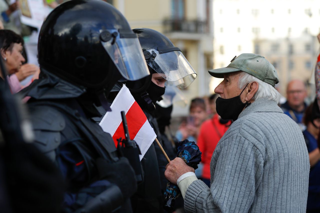 Een oudere betoger staat oog in oog met de oproerpolitie.
