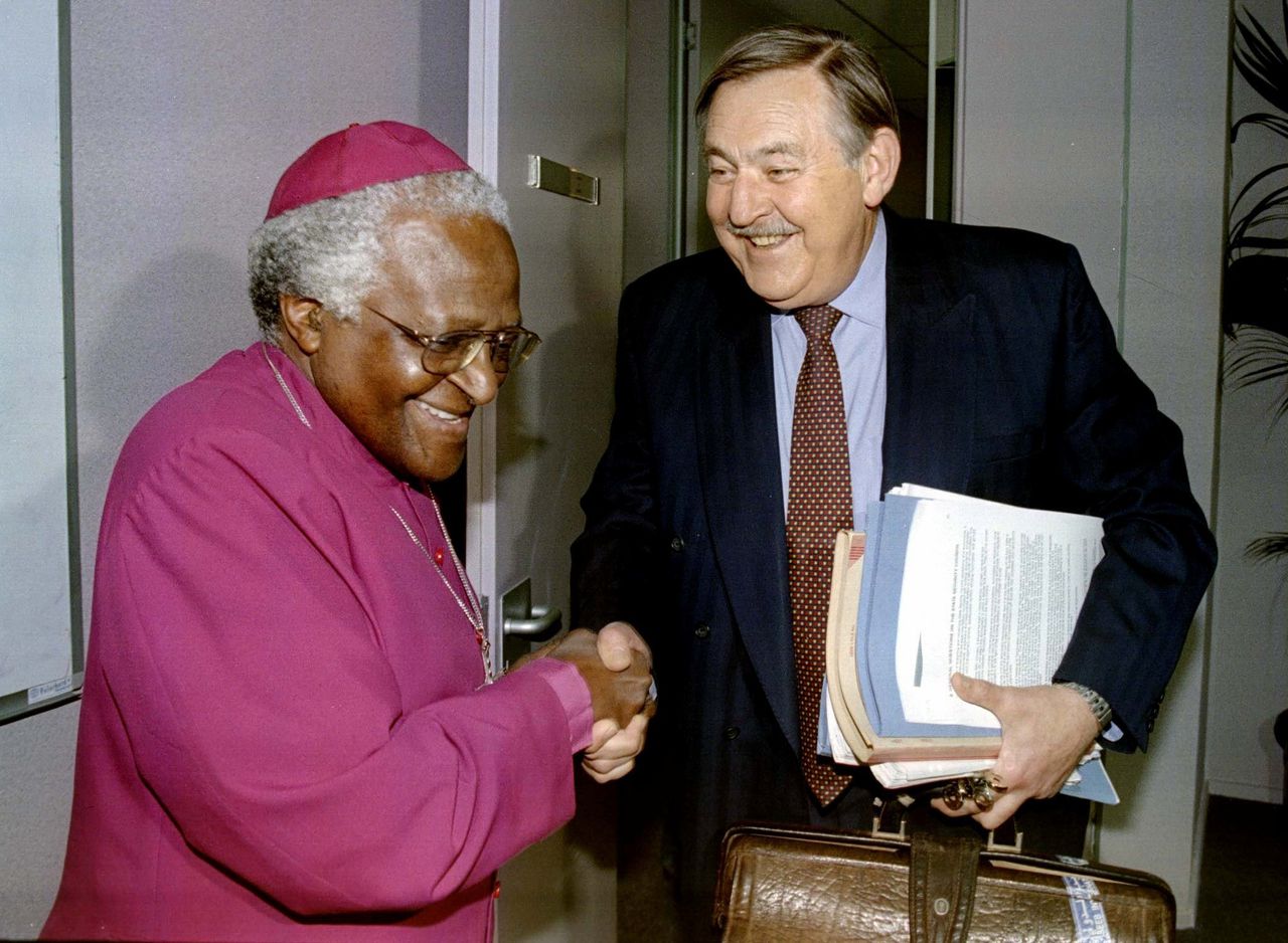 Pik Botha (rechts) schudt de hand van aartsbisschop Desmond Tutu.