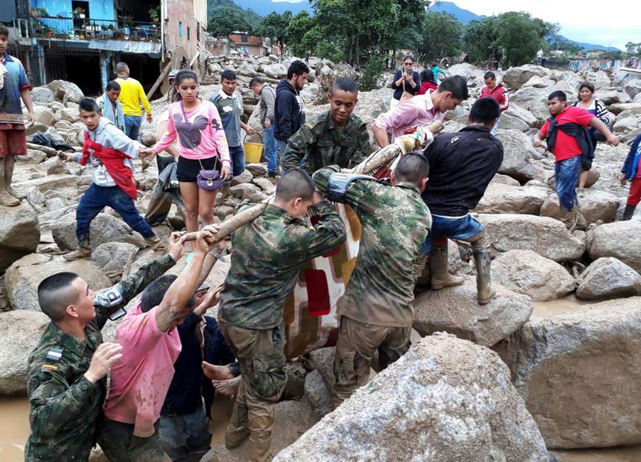 Militairen en inwoners evacueren een slachtoffer van de modderstroom in Mocoa.