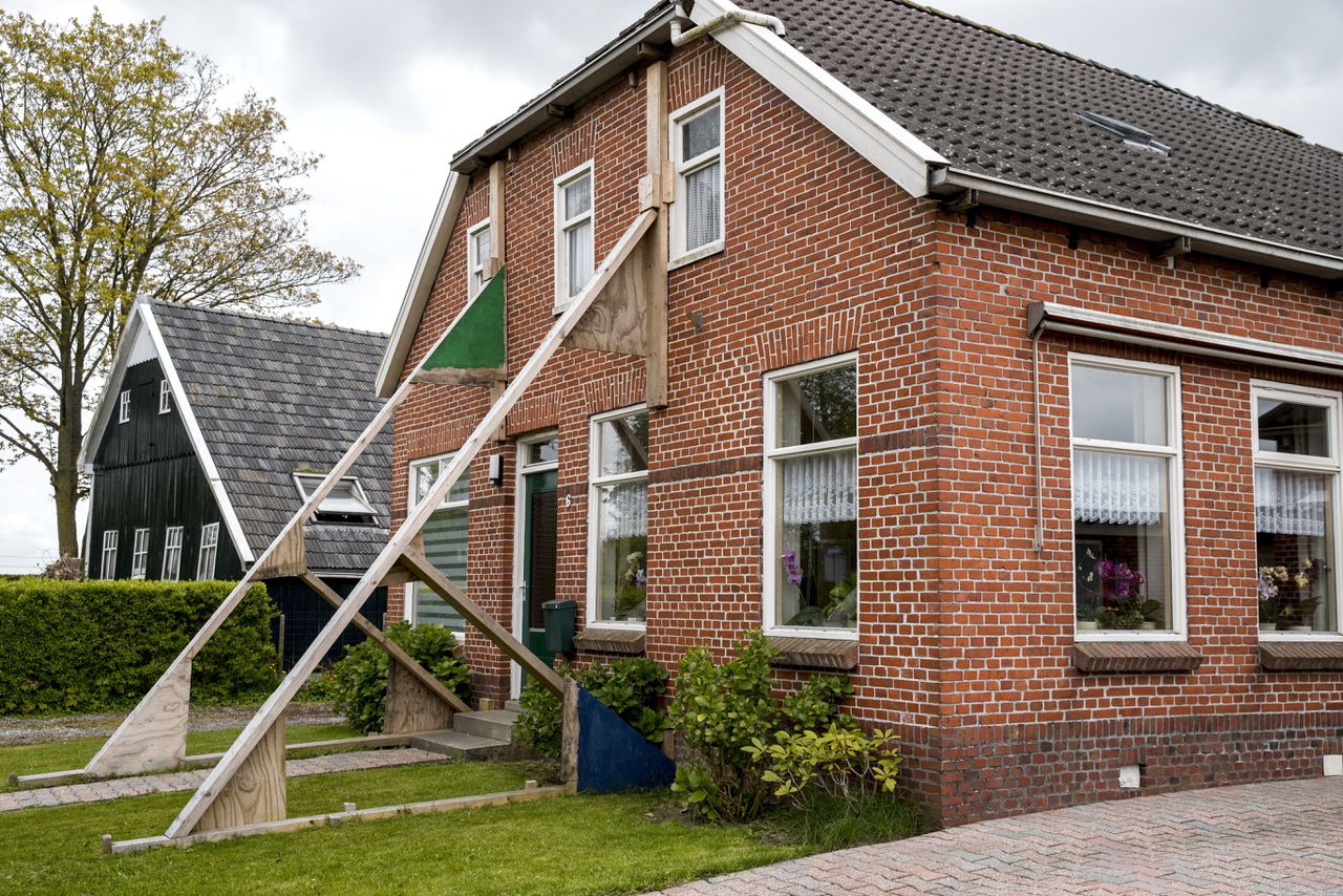 Een beschadigde woning wordt versterkt door stutten in aardbevingsgebied Loppersum.