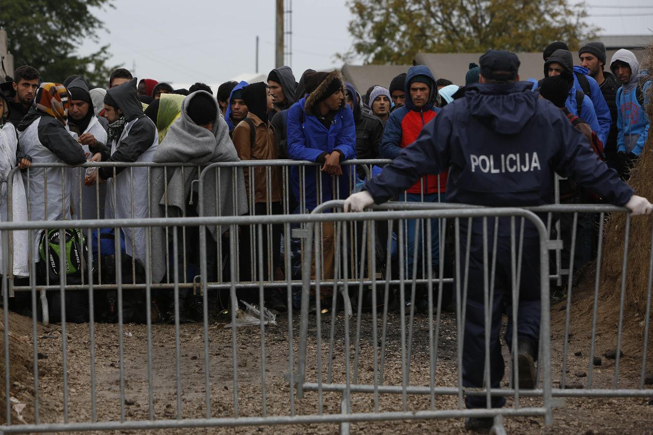 Migranten gewikkeld in dekens wachten aan de Kroatische kant van de grens op bussen om naar Hongarije gebracht te worden.