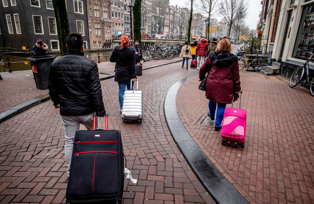 Toeristen met rolkoffers in Amsterdam. Vorig jaar werden in totaal bijna 1,7 miljoen overnachtingen in Amsterdam geboekt via Airbnb.