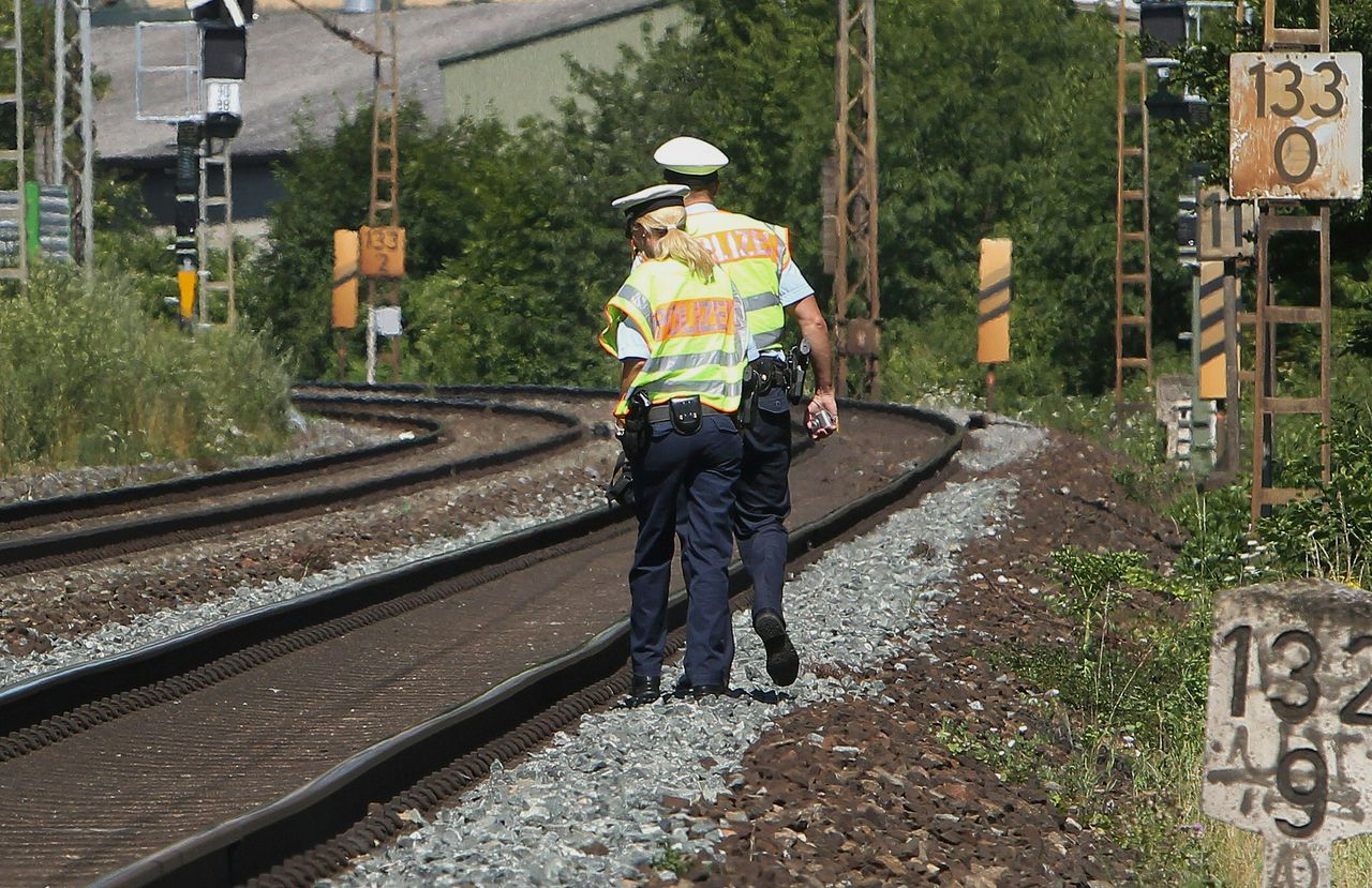 Duitse politieagenten lopen bij het spoor in de buurt van de plek waar de trein tot stilstand kwam.