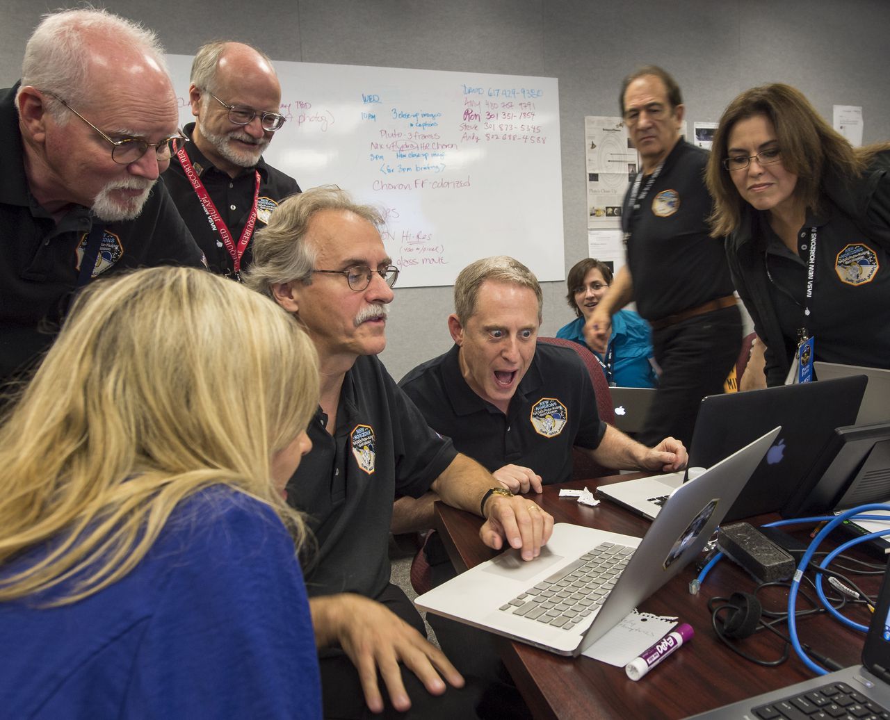 Onderzoeker Alan Stern van het Southwest Research Institute (midden) verzamelt zijn team om de nieuwe foto's van New Horizons voor de eerste keer te bekijken.