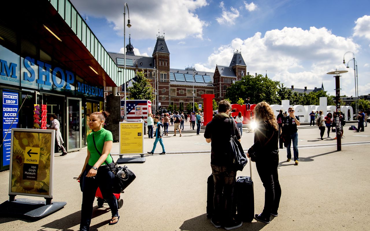Toeristen met rolkoffers op het Museumplein in Amsterdam. Rolkoffers zijn een van de problemen van toenemende populariteit van AirBnB.