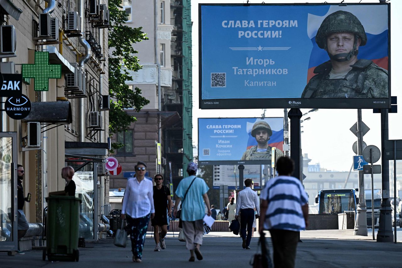 Mensen lopen langs reclameborden waarop de foto’s van Russische soldaten, de ‘helden van Rusland’, zijn opgehangen. Straatbeeld van Moskou op 24 augustus 2022.