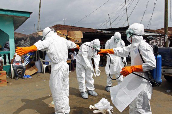 Hulpverleners van het 'begrafenisteam' desinfecteren elkaar nadat ze het lichaam van een aan ebola overleden patiënt hebben aangeraakt.