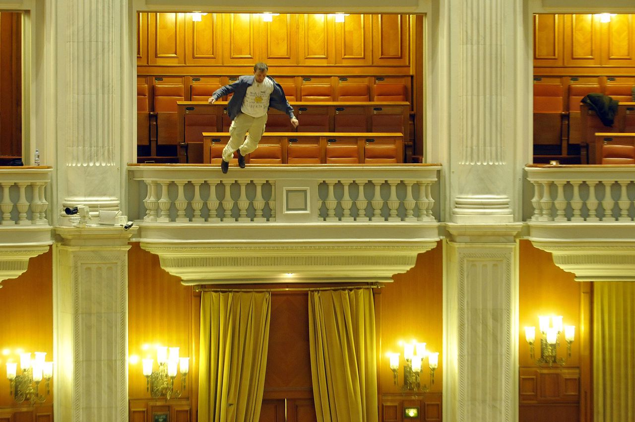 A public television employee jumps off the Parliament hall's balcony to protest at the government's austerity drive, including wage cuts and tax hikes in the recession-hit economy as Prime Minister Emil Boc addresses during a no-confidence vote over IMF-backed wage reforms in Bucharest, December 23, 2010. State news agency Agerpres said the man, a father of two in his forties, was seriously injured. He was wearing a shirt with the words, "You killed our children's future, you sold us". REUTERS/Bogdan Stamatin/Mediafax Foto (ROMANIA - Tags: SOCIETY POLITICS CIVIL UNREST) NO SALES. NO ARCHIVES. FOR EDITORIAL USE ONLY. NOT FOR SALE FOR MARKETING OR ADVERTISING CAMPAIGNS. NO THIRD PARTY SALES. NOT FOR USE BY REUTERS THIRD PARTY DISTRIBUTORS. SENSITIVE MATERIAL. THIS IMAGE MAY OFFEND OR DISTURB. ROMANIA OUT. NO COMMERCIAL OR EDITORIAL SALES IN ROMANIA. THIS IMAGE HAS BEEN SUPPLIED BY A THIRD PARTY. IT IS DISTRIBUTED, EXACTLY AS RECEIVED BY REUTERS, AS A SERVICE TO CLIENTS